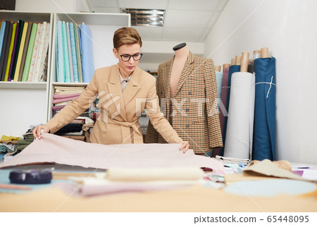 Tailor working with fabric in workshop 65448095