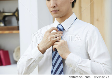 A young man tying a tie 65448373