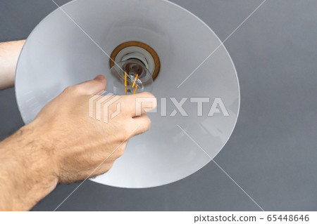 Close-up. A hand changes a light bulb in a stylish Close-up. A hand changes a light bulb in a stylish 65448646