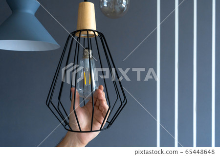 Close-up. A hand changes a light bulb in a stylish Close-up. A hand changes a light bulb in a stylish 65448648