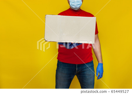 Delivery man in medical mask holding a cardbox on Delivery man in medical mask holding a cardbox on 65449527