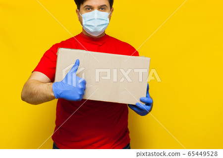 Delivery man in medical mask holding a cardbox on Delivery man in medical mask holding a cardbox on 65449528