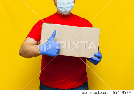 Delivery man in medical mask holding a cardbox on 65449529