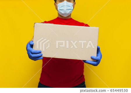 Delivery man in medical mask holding a cardbox on Delivery man in medical mask holding a cardbox on 65449530