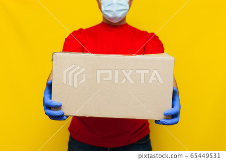 Delivery man in medical mask holding a cardbox on Delivery man in medical mask holding a cardbox on 65449531