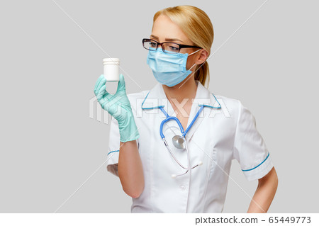 medical doctor nurse woman wearing protective mask and rubber or latex gloves - holding can of pills medical doctor nurse woman wearing protective mask and rubber or latex gloves - holding can of pills 65449773
