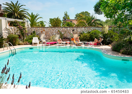Men sunbathing beside the swimming pool Men sunbathing beside the swimming pool 65450483