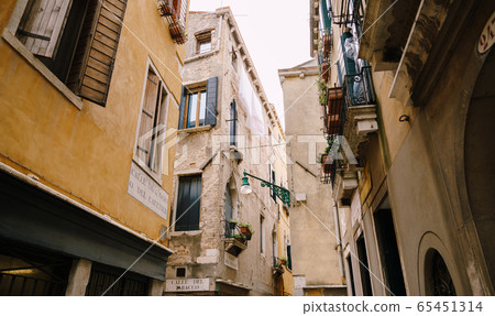 An old street lamp, on the corner of the facade of a house, on a street in Venice, Italy. An old street lamp, on the corner of the facade of a house, on a street in Venice, Italy. 65451314