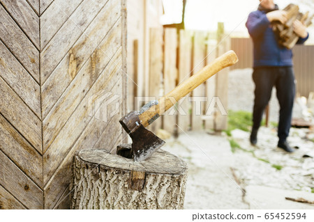 Man with an ax chops wood for heating Man with an ax chops wood for heating 65452594