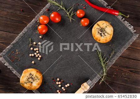 Wheat cakes, fresh tomatoes, rosemary and chickpeas, on a dark background. 65452830