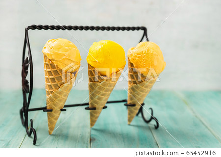 Three yellow ice cream cones staying in a stand on Three yellow ice cream cones staying in a stand on 65452916