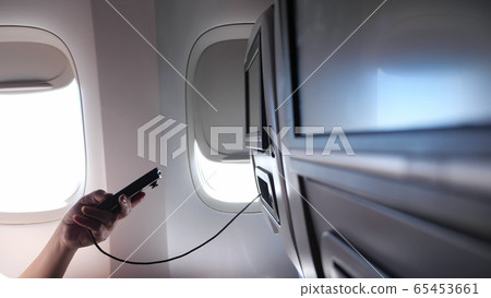 woman hand uses remote control for seatback TV set screen 65453661