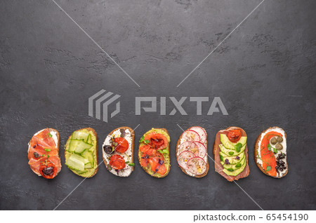 Homemade sandwiches with bread and various ingredients and spices on a dark background. Healthy Homemade sandwiches with bread and various ingredients and spices on a dark background. Healthy 65454190