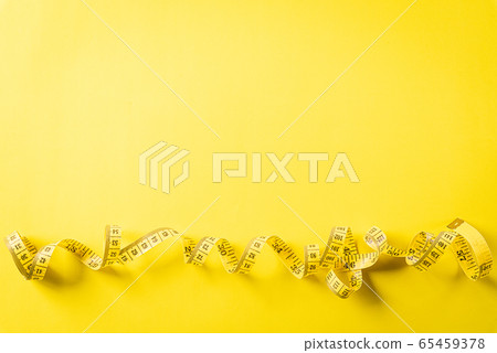 Measuring tape lying on a yellow background, 65459378