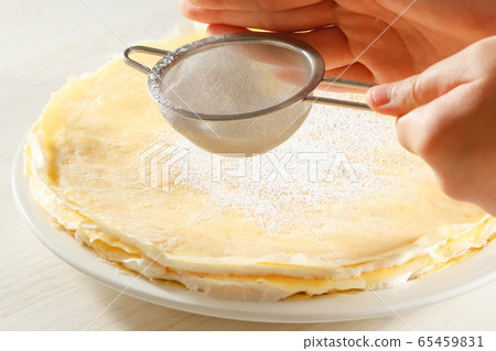 Sprinkle powdered sugar on a handmade cake 65459831