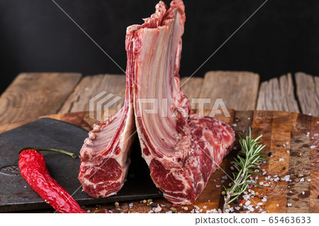 Raw lamb meat in a carnage on wooden background Raw lamb meat in a carnage on wooden background 65463633