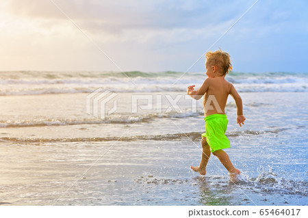 Child run with splashes by water pool along sea Child run with splashes by water pool along sea 65464017