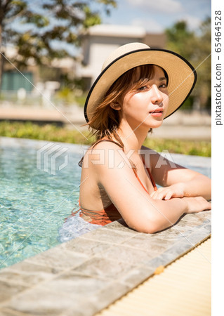一個女人在游泳池旁放鬆的泳裝 一個女人在游泳池旁放鬆的泳裝 65464528