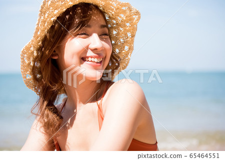 A woman in a swimsuit sitting on the beach A woman in a swimsuit sitting on the beach 65464551