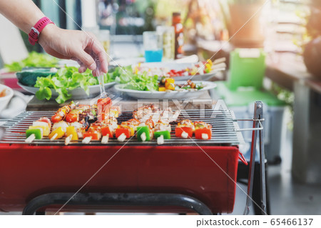 A man grilling pork and barbecue in dinner party. 65466137