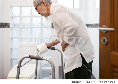 Senior woman with diarrhea holding tissue roll near a toilet bowl,elderly have abdominal pain,stomach ache,constipation in bathroom,sick people hand touch the belly diarrhea,irritable bowel syndrome 65467394