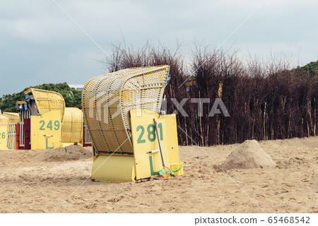 Sandy beach and typical hooded beach chairs in Cuxhaven in the North Sea coast Sandy beach and typical hooded beach chairs in Cuxhaven in the North Sea coast 65468542