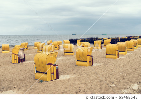 Sandy beach and typical hooded beach chairs in Cuxhaven in the North Sea coast Sandy beach and typical hooded beach chairs in Cuxhaven in the North Sea coast 65468545