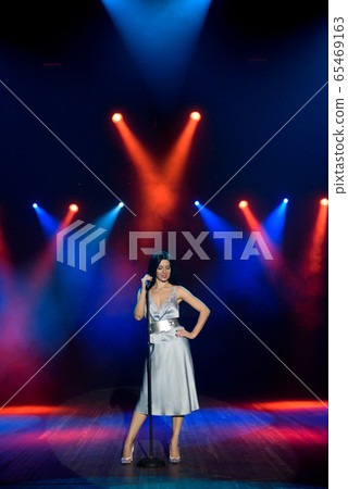Bright stage lighting. Vocalist singing to microphone. 65469163