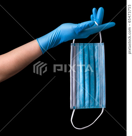 Doctor's hand in medical gloves wearing a mask isolated on black Doctor's hand in medical gloves wearing a mask isolated on black 65473755