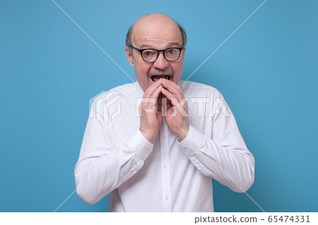 Amazed afraid senior man is shocked with news 65474331