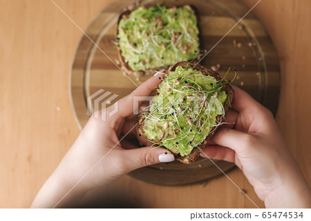 Top view of woman hold rye toast bread with guacamole on top. Gluten free Top view of woman hold rye toast bread with guacamole on top. Gluten free 65474534