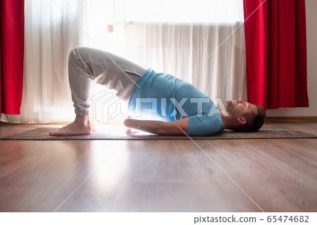 Young man doing wheel pose in the living room Young man doing wheel pose in the living room 65474682