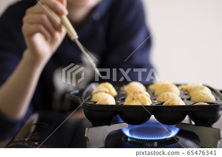 Woman baking Takoyaki with a pick Woman baking Takoyaki with a pick 65476341