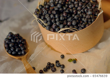 Blueberries in a wooden box, next to a wooden spoon with berries, lie on a white canvas, still life with wood bowl with berries Blueberries in a wooden box, next to a wooden spoon with berries, lie on a white canvas, still life with wood bowl with berries 65476639