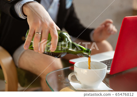 Young man without pants but in jacket working on a computer, laptop. Remote office during coronavirus, fun and comfortable work in underpants 65476812