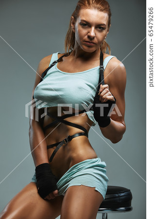 Beautiful tanned red-haired girl dancer posing on a gray background in shorts and a t-shirt sexually posing. Beautiful female body dancing, training. Beautiful tanned red-haired girl dancer posing on a gray background in shorts and a t-shirt sexually posing. Beautiful female body dancing, training. 65479266