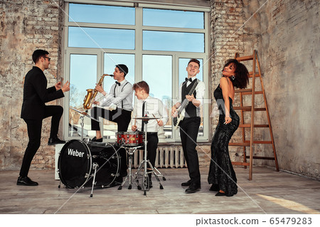 A multiracial music group performs in a recording studio. A group of international musicians rehearsing a concert performance. Vocalist, ram, guitarist A multiracial music group performs in a recording studio. A group of international musicians rehearsing a concert performance. Vocalist, ram, guitarist 65479283