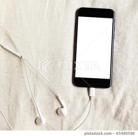 Smartphone with headphones lies in rumpled bed Smartphone with headphones lies in rumpled bed 65480590