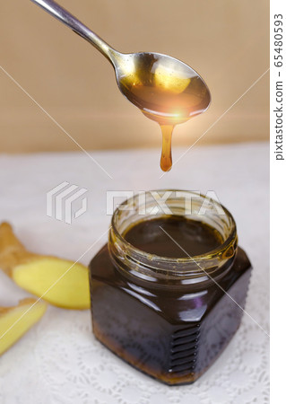 Buckwheat honey pours from spoon into jar 65480593