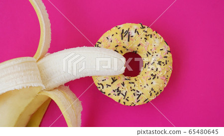 Sweet donut and banana on pink color background. Erotic concept 65480645