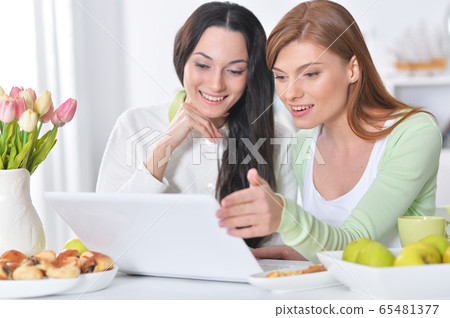 Two female friends at desk posing at home Two female friends at desk posing at home 65481377