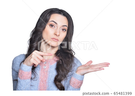 Beautiful brunette young woman pointing to the right against white background 65481399
