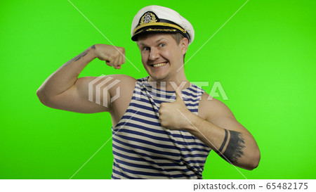 Young sailor man shows muscles, looking at camera. Seaman guy in sailor's vest Young sailor man shows muscles, looking at camera. Seaman guy in sailor's vest 65482175