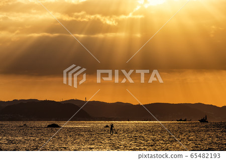 The sky that shines beautifully in twilight rays, the shining coast, fishing boats, and surfers 65482193