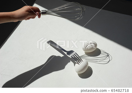 Egg with shadow from the fork. Minimalism. Cooking pastries, omelets. Easy. Whisk for whipping. 65482718