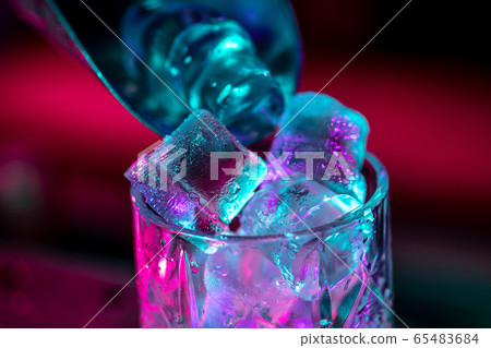 Close up of alcoholic cocktail, beverage, drink, glass full of ice in multicolored neon light Close up of alcoholic cocktail, beverage, drink, glass full of ice in multicolored neon light 65483684