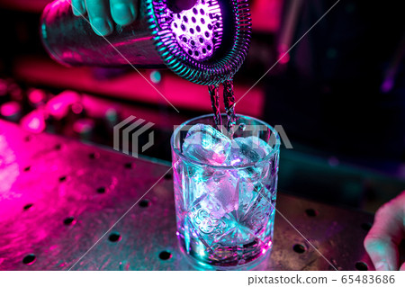 Close up of alcoholic cocktail, beverage, drink, glass full of ice in multicolored neon light 65483686