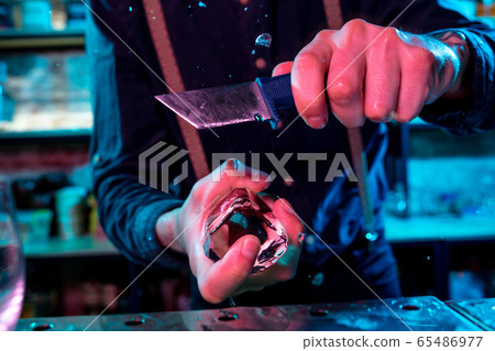 Close up of barman crushing a big piece of ice on the bar counter with a special bar equipment on it for a cocktail Close up of barman crushing a big piece of ice on the bar counter with a special bar equipment on it for a cocktail 65486977
