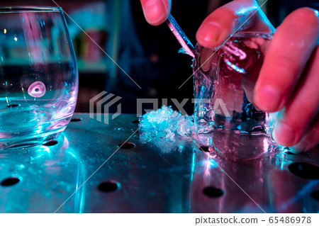 Close up of barman crushing a big piece of ice on the bar counter with a special bar equipment on it for a cocktail Close up of barman crushing a big piece of ice on the bar counter with a special bar equipment on it for a cocktail 65486978