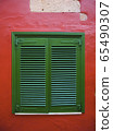 Old green window in red wall 65490307